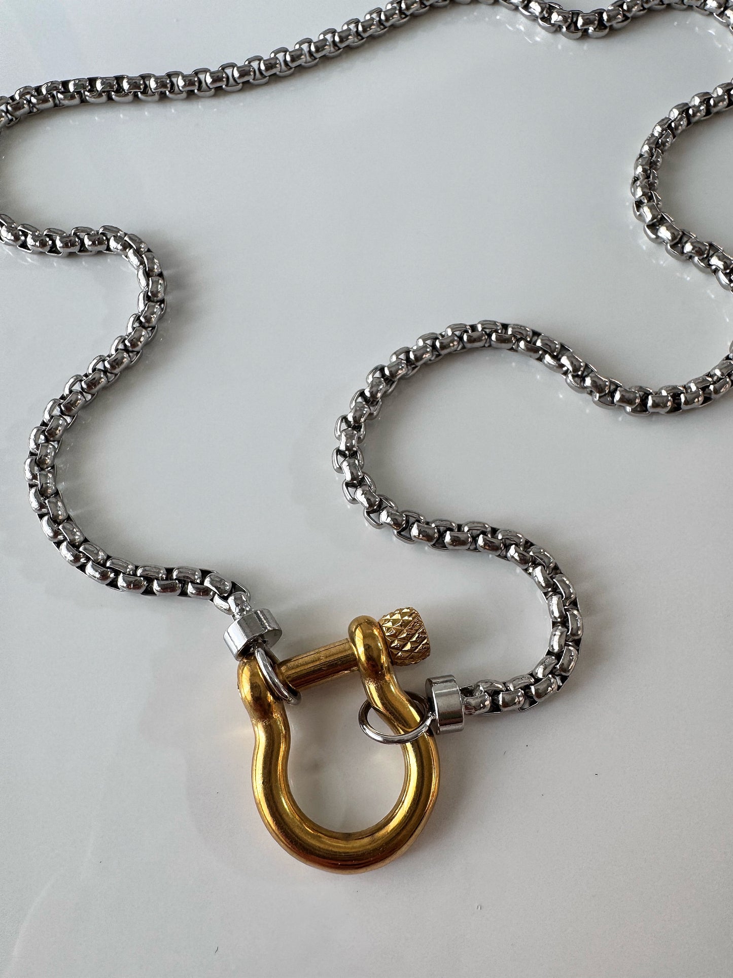Close-up of chunky gold clasp on silver chain necklace showing mixed metals.